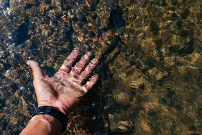 High angle view of hand touching water