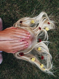 High angle view of young woman covering face with hands while lying on grassy field