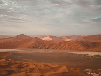 Scenic view of sand dunes against cloudy sky