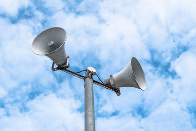 Low angle view of megaphones against cloudy sky