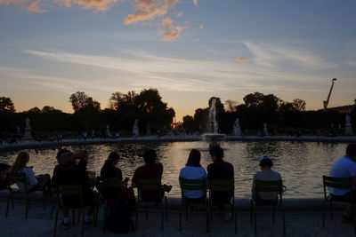 Group of people sitting on seat against sky during sunset