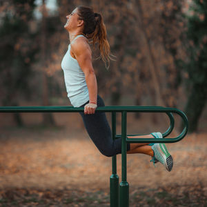 Side view of woman exercising on bars in park