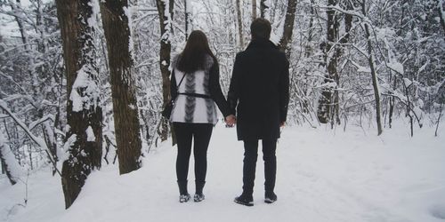 Rear view of women walking in forest during winter