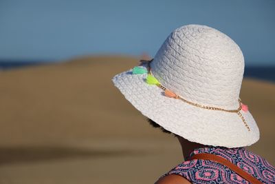 Rear view of woman wearing hat at beach against clear sky