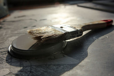 Brush placed on lid of a can on the floor to dry focus on brush hair and lid
