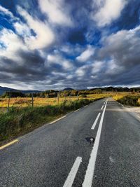 Road passing through landscape against cloudy sky