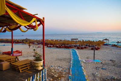 Deck chairs on beach against sky