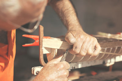 Close-up of man working on wooden boat model