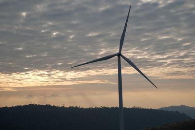 Silhouette of wind turbine against sky during sunset