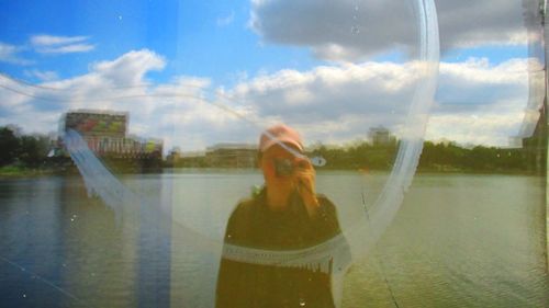 Reflection of woman on glass against sky