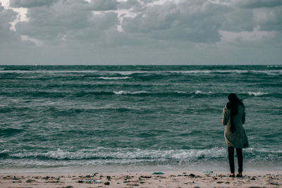 Woman standing at beach against sky