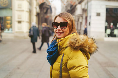 Portrait of young woman wearing warm clothing standing on street in city