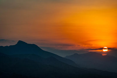 Scenic view of silhouette mountains against orange sky