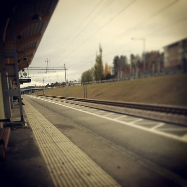 transportation, railroad track, rail transportation, public transportation, railroad station platform, sky, power line, mode of transport, the way forward, train - vehicle, electricity pylon, railroad station, road, diminishing perspective, travel, train, railway track, vanishing point, empty, surface level