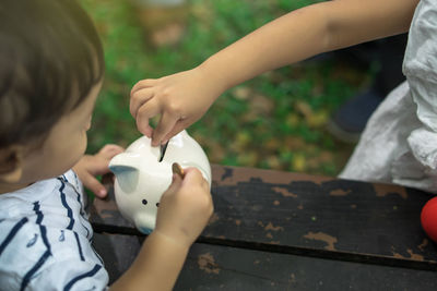 Brother and sister inserting coins in piggy bank