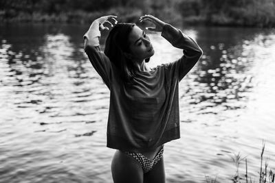 Young woman looking away while standing in lake