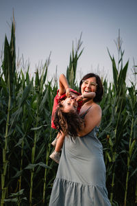 Mother with dark hair and daughter with light hair having fun outdoors corn field
