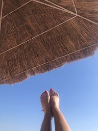 Low section of woman with feet up against clear sky