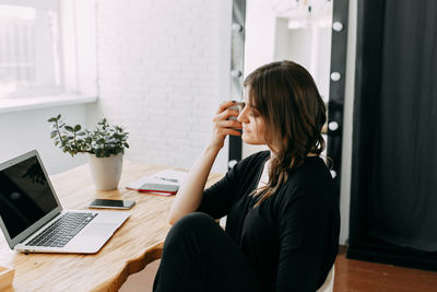 Business girl freelancer in casual clothes works using wireless technology in the home office