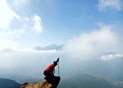 Man with umbrella on mountain against sky