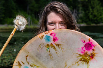 Portrait of beautiful young woman holding dandelion