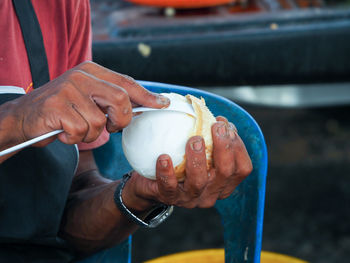 Midsection of man removing coconut from shell