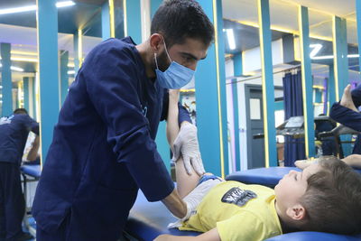 A male physical therapist treats a child in a physical therapy center, physiotherapy. war casualties