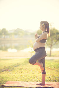 Pregnant woman doing yoga on field