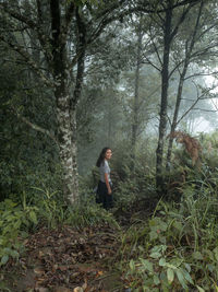 Side view of woman standing in forest