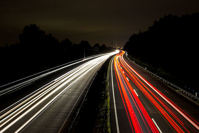 Light trails on roads against sky at night