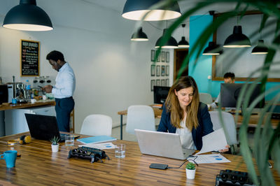 Portrait of woman using mobile phone while sitting on table