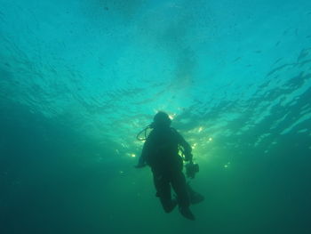 Low angle view of silhouette man scuba diving undersea