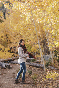 Full length of woman standing in forest during autumn