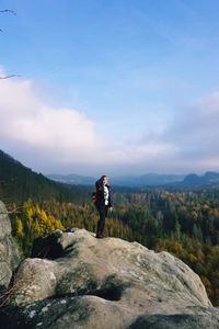 Man standing on rock looking at mountain against sky