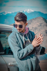 Young man using mobile phone while sitting on car