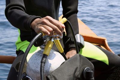 Midsection of man holding aqualung on boat in sea