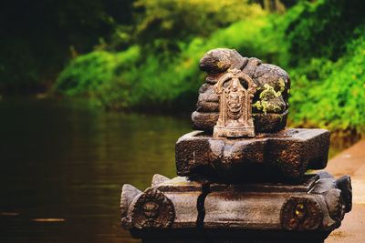 Close-up of old statue against lake