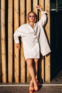 Portrait of young woman standing against planks