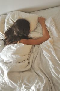 High angle view of young woman sleeping on bed at home