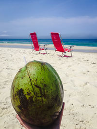 Deck chairs on sand at beach against sky