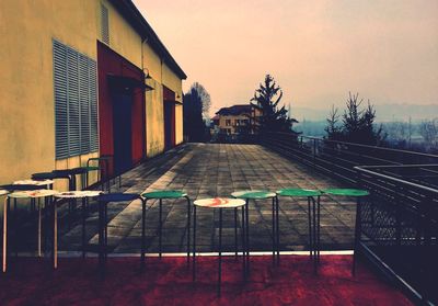 Empty chairs and tables against buildings in city