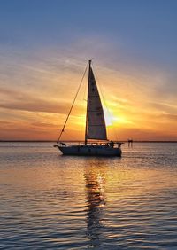 Sailboat sailing on sea against sky during sunset