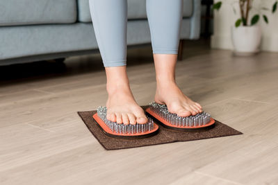 Woman standing on wooden yoga board with nails for yoga practice and meditation. sadhu board 