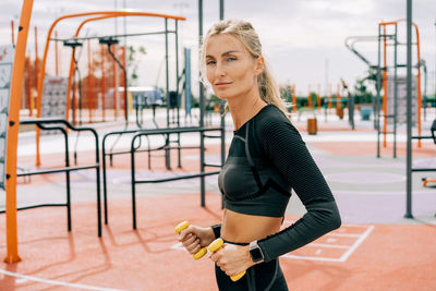 Sportswoman in training with dumbbells outside.