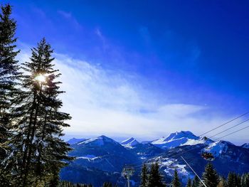 Low angle view of snowcapped mountains against blue sky