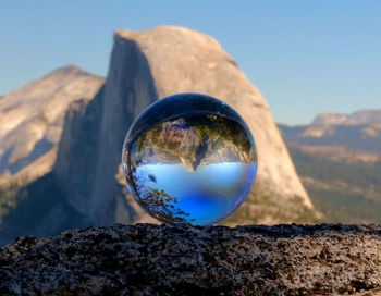 Close-up of crystal ball against mountain