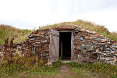 Old wooden house on field against sky