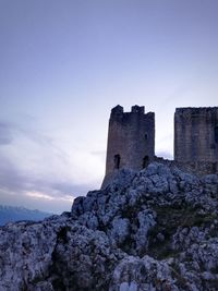 Low angle view of fort on rock formation against sky