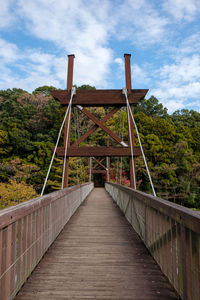 Footbridge leading to bridge against sky