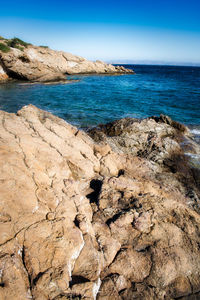 Scenic view of rocks on shore against clear sky